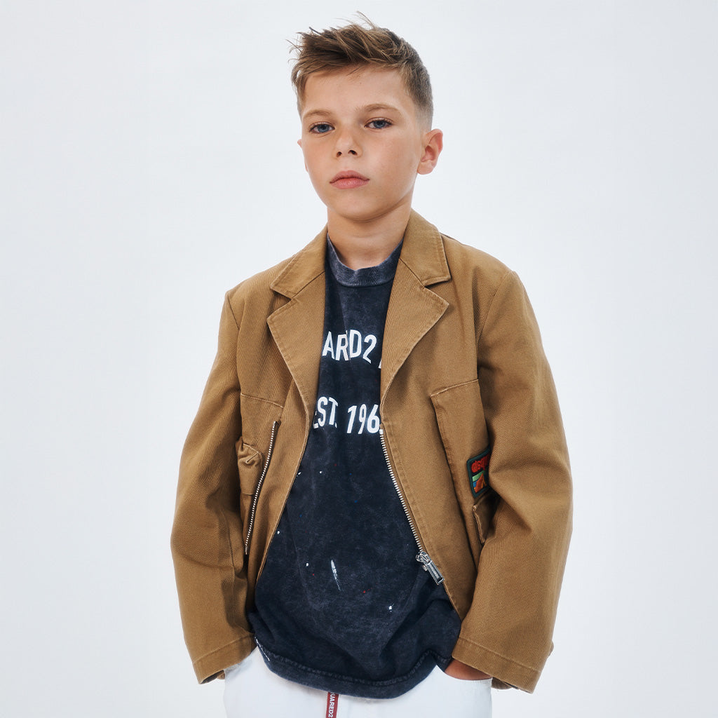 A boy wearing a cool outfit with a brown jacket and a blue t-shirt