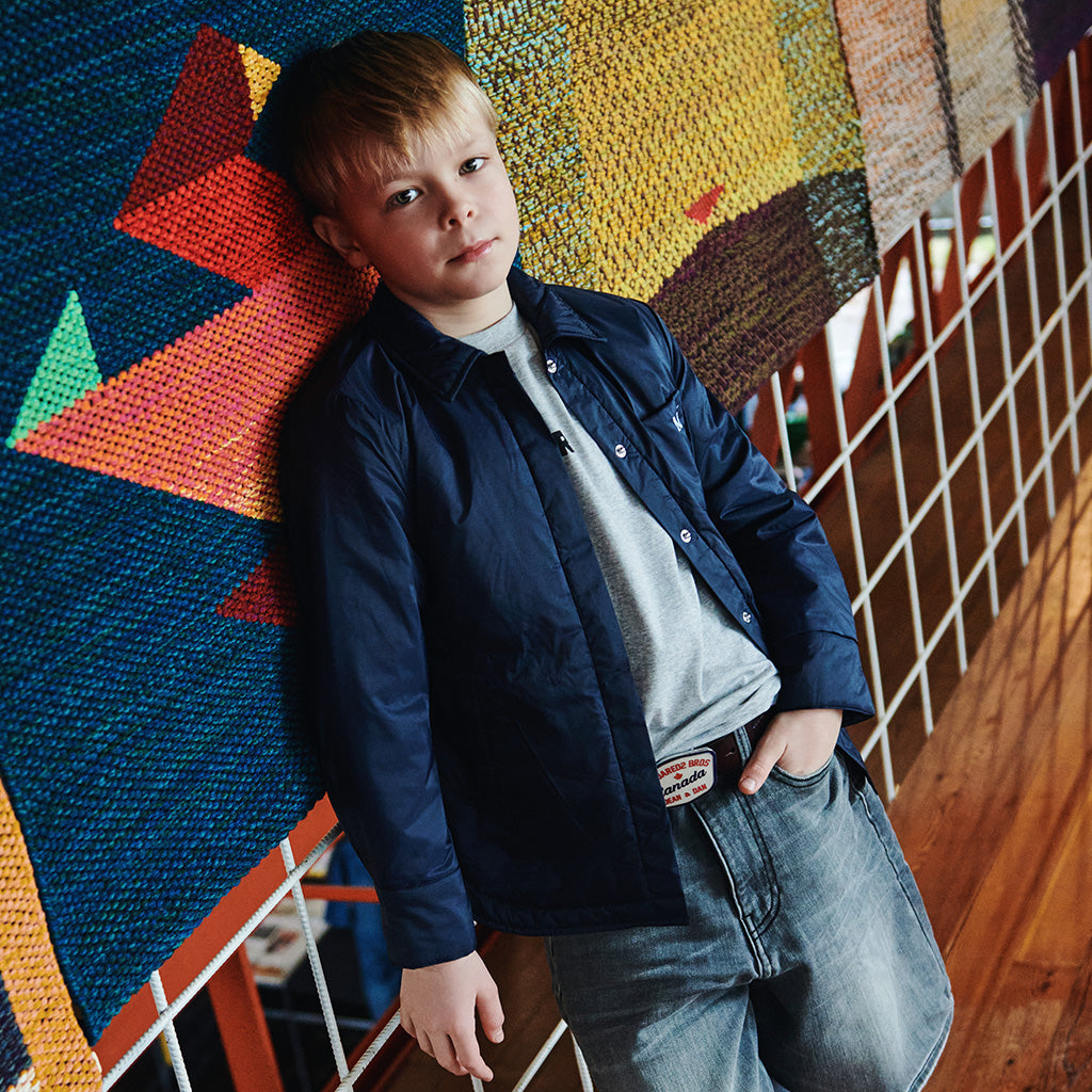 A boy sitting down and wearing a stylish summer look